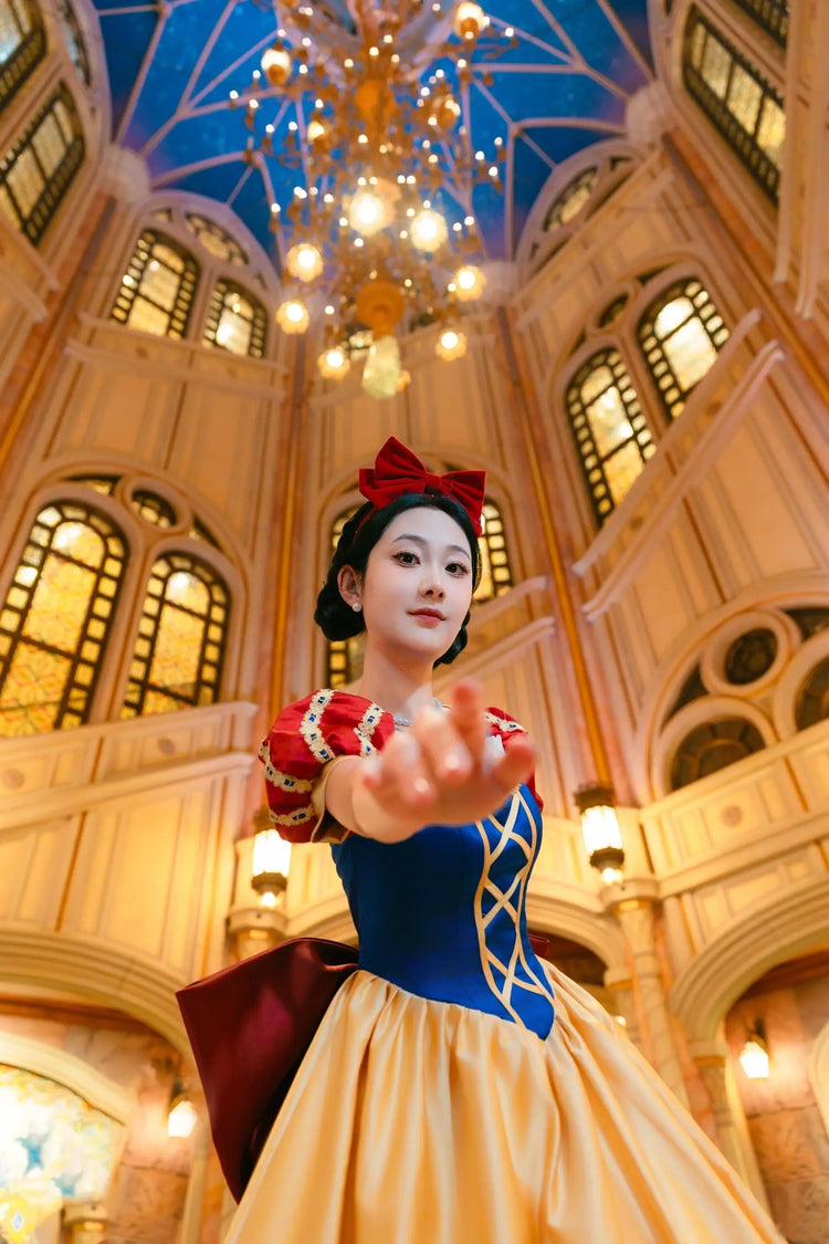 Person in Snow White costume standing in a grand hall with chandelier
