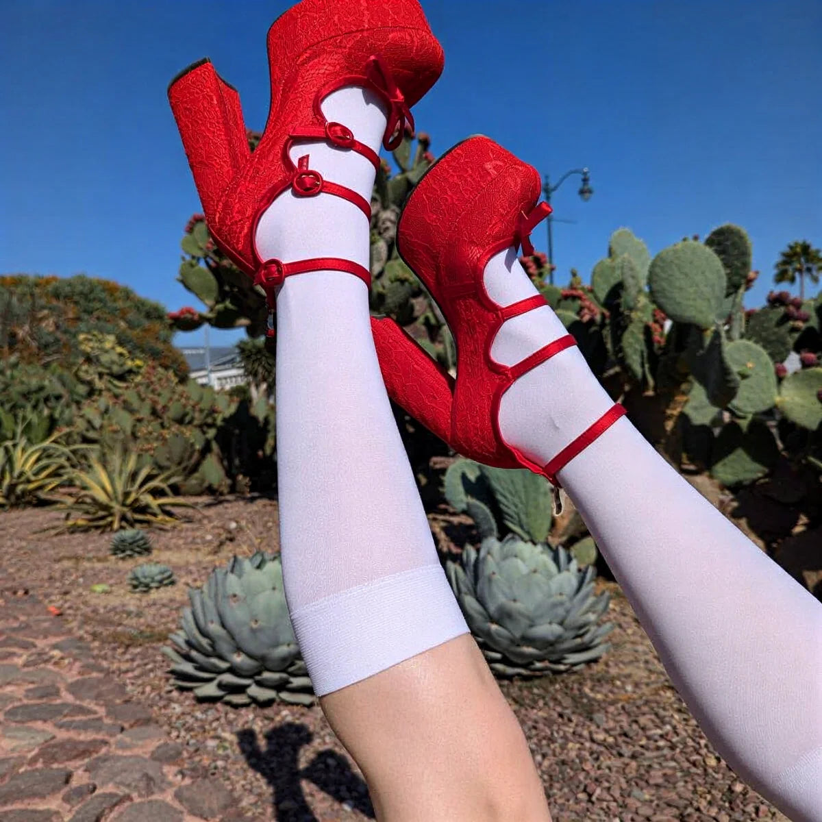 Red lace-up platform heels with white socks, featuring bold straps and textured fabric.