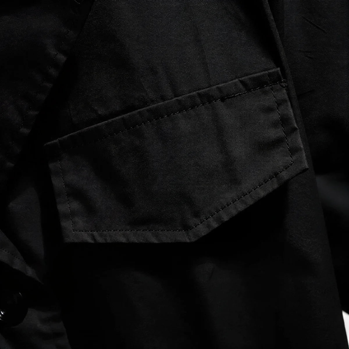 Black dress with textured fabric and flap pocket detail.