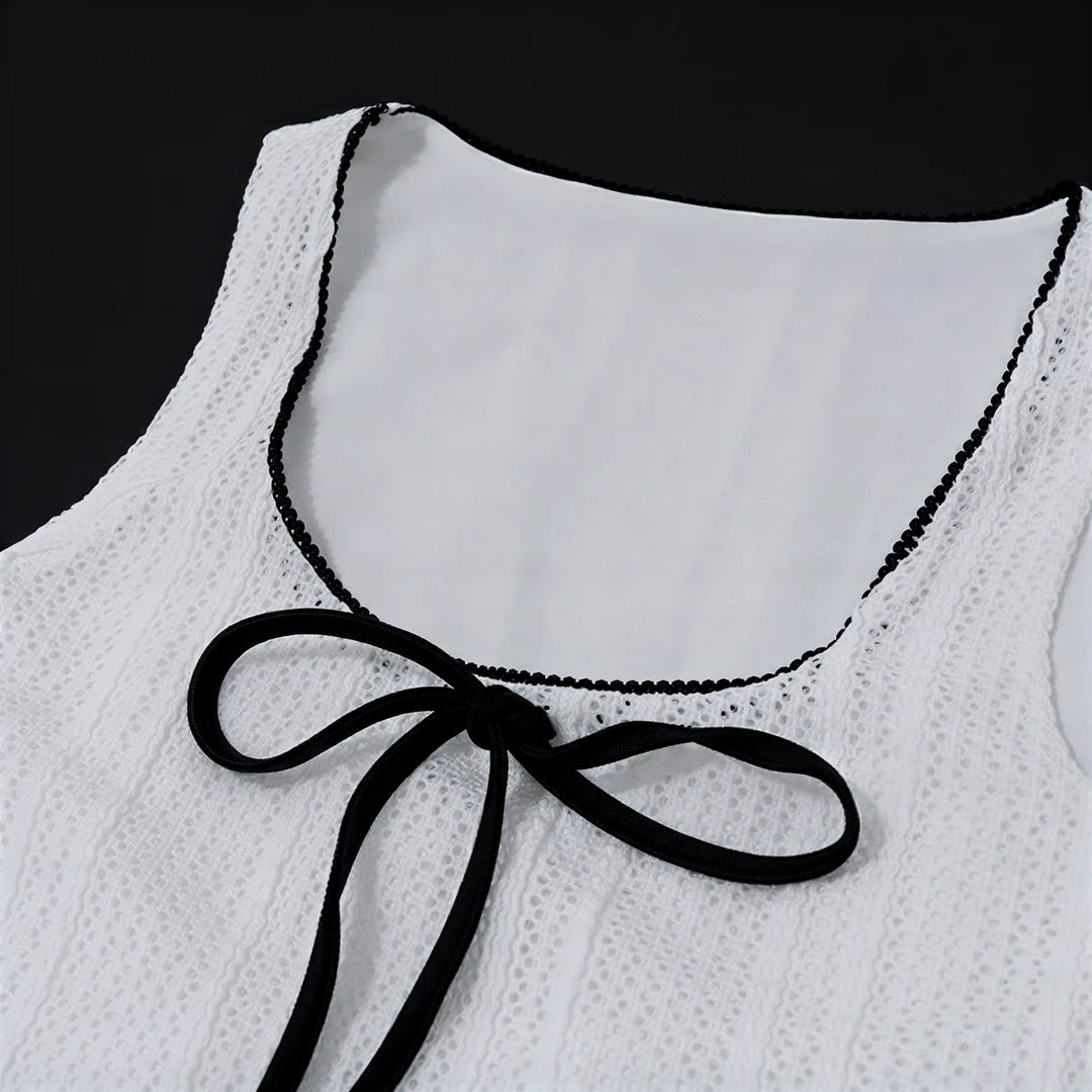 White lace dress with black trim and bow at neckline.