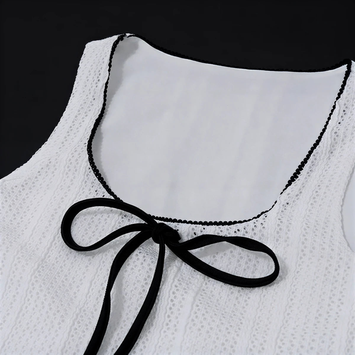 White lace dress with black trim and bow at neckline.