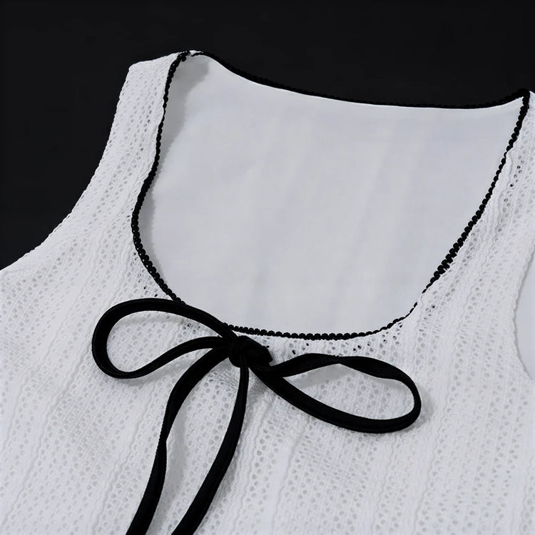 White lace dress with black trim and bow at neckline.