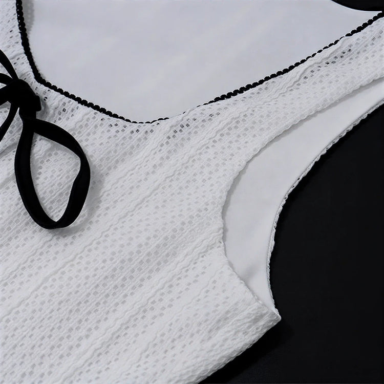 White lace dress with black trim and tie detail at neckline.