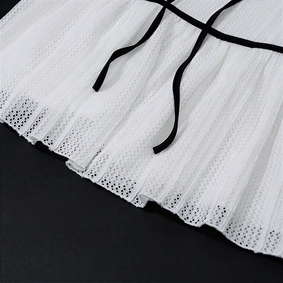 White eyelet skirt with black ribbon ties at waist.