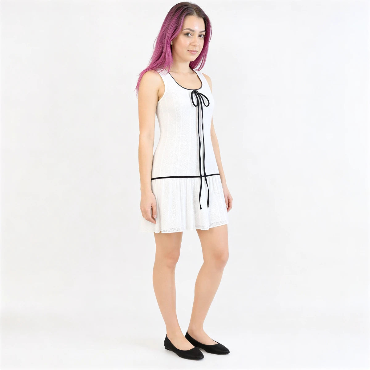 White pleated sleeveless dress with black trim and tie detail.