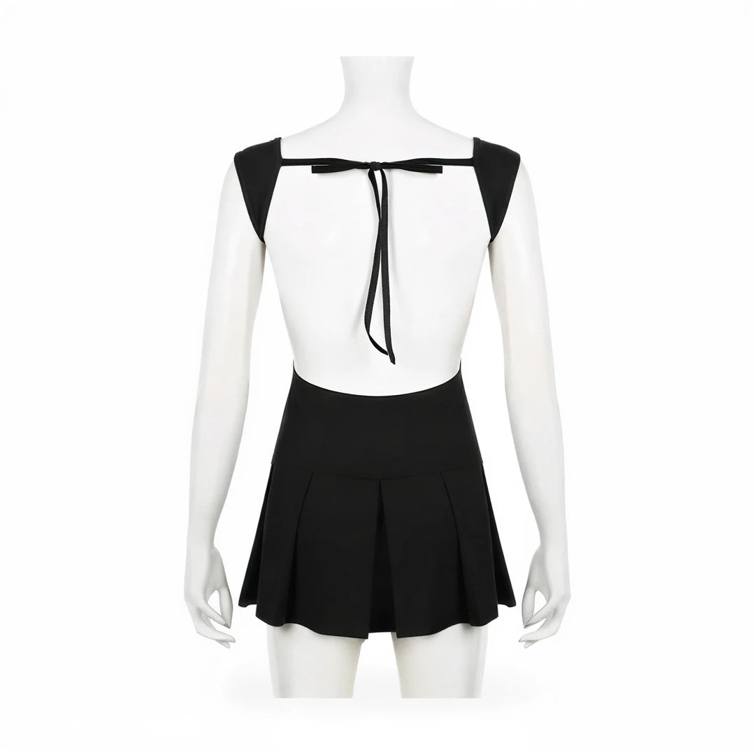 Backless mini dress in black, featuring tie-back detail and pleated skirt.