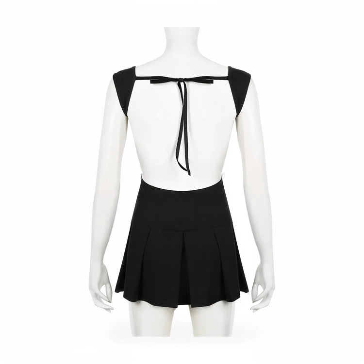 Backless mini dress in black, featuring tie-back detail and pleated skirt.